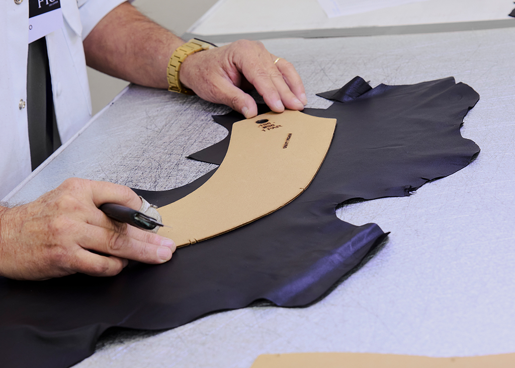 Artesão cortando couro com molde na mesa de corte
